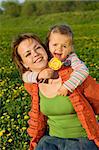 Woman and little girl having fun on the spring meadow full of flowers