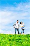 Happy young family on green grass over deep blue sky