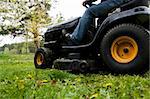 Worker mowing with black riding lawn mower
