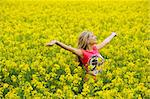 happy blond girl with open arms in a yellow field smiling