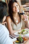 A young woman smiling whilst eating dinner at a restaurant