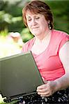 happy woman with laptop relaxing on grass