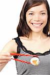 Smiling young woman presenting a maki sushi. Shallow depth of field, focus on eyes. Isolated on white.