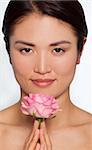 Studio shot of a beautiful young Japanese woman holding a pink rose between her clasped hands