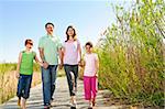 Portrait of happy family of four walking on boardwalk