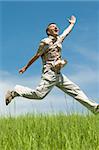 a happy man is running and jumping over the green meadow