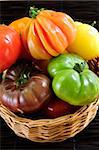 Wicker basket full of multi colored heirloom tomatoes