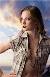 sensual fashion portrait of pretty young blond with open shirt and clouds behind