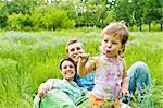 Lovely toddler eating flower, smiling parents in back