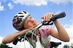 Healthy young girl with bicycle looking at the sun