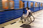 Woman in wheelchair near to passing train of subway