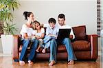 Happy family playing together with a laptop on a sofa