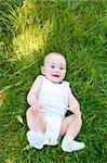 Smiling baby lies in the green grass