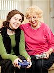Grandmother and teen granddaughter bonding by playing video games together.