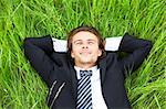 Well-dressed young businessman is resting in a field