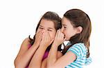 Two Caucasian girls telling secrets on white background