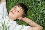 Dreamy teenager is relaxing, and he lies on the grass