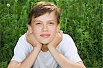 Dreamy teenager is relaxing, and he sit on the grass