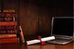 Antique books, diploma with laptop on school desk