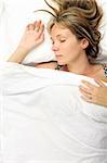 Woman asleep in a bed with white sheets