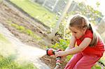 Little girl watering the grass in the garden