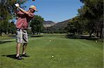 A Man golfing swinging his club toward the tee