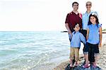 Happy family standing on shore at the beach