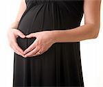 belly of pregnant woman in black dress with hands in heart gesture