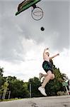 young boy jumping while playing basketball alone