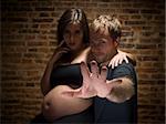 A man try to stop the picture to be taken.Woman on her eighth month of pregnancy. Focus on hand.