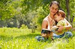 Happy mother and son reading a book outdoors