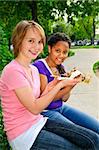 Two teenage girls sitting and eating pizza