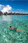 A boy swims on clear crystal ocean fills with coral during vacation