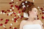 Redhead beautiful woman with colorful rose petals on hair