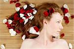 Redhead beautiful woman with colorful rose petals on hair