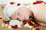 Beautiful woman relaxing on spa with colorful flower petals, aromatherapy