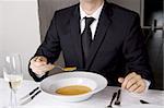 Business man is having lunch at a frensh gourmet restaurant. He is having lobster soup.