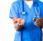 Close-up of an friendly Afro-American doctor in scrubs with pills and glass of water