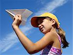 young girl with paper plane against blue sky