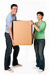 A happy and attractive young couple holding a cardboard box together.  They are smiling and are looking directly at the camera.  Vertically framed shot.