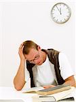 A young student working on his homework while the clock is ticking