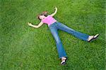 Young Woman relaxing lying on green grass