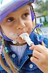 child wiht a helmet eating an ice-cream outdoor