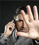 Angry businessman saying stop with hand,talking to a mobile phone