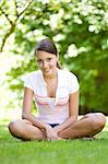 happy young woman sitting on grass in park