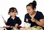 Two asian children have dinner,isolated on a white background.