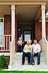 Young family sitting on front steps of house