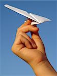 child hand with paper plane against blue sky
