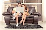 Caucasian couple seated on couch and using laptop