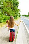 Mother and daughter sitting on a suitcase and trying to catch a car